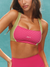 Woman wearing a pink and green sports bra with 'SET' branding against a teal background <model-info>Kushi wears a size XS and is 5’8, 24” waist, 32C bust.</model-info>