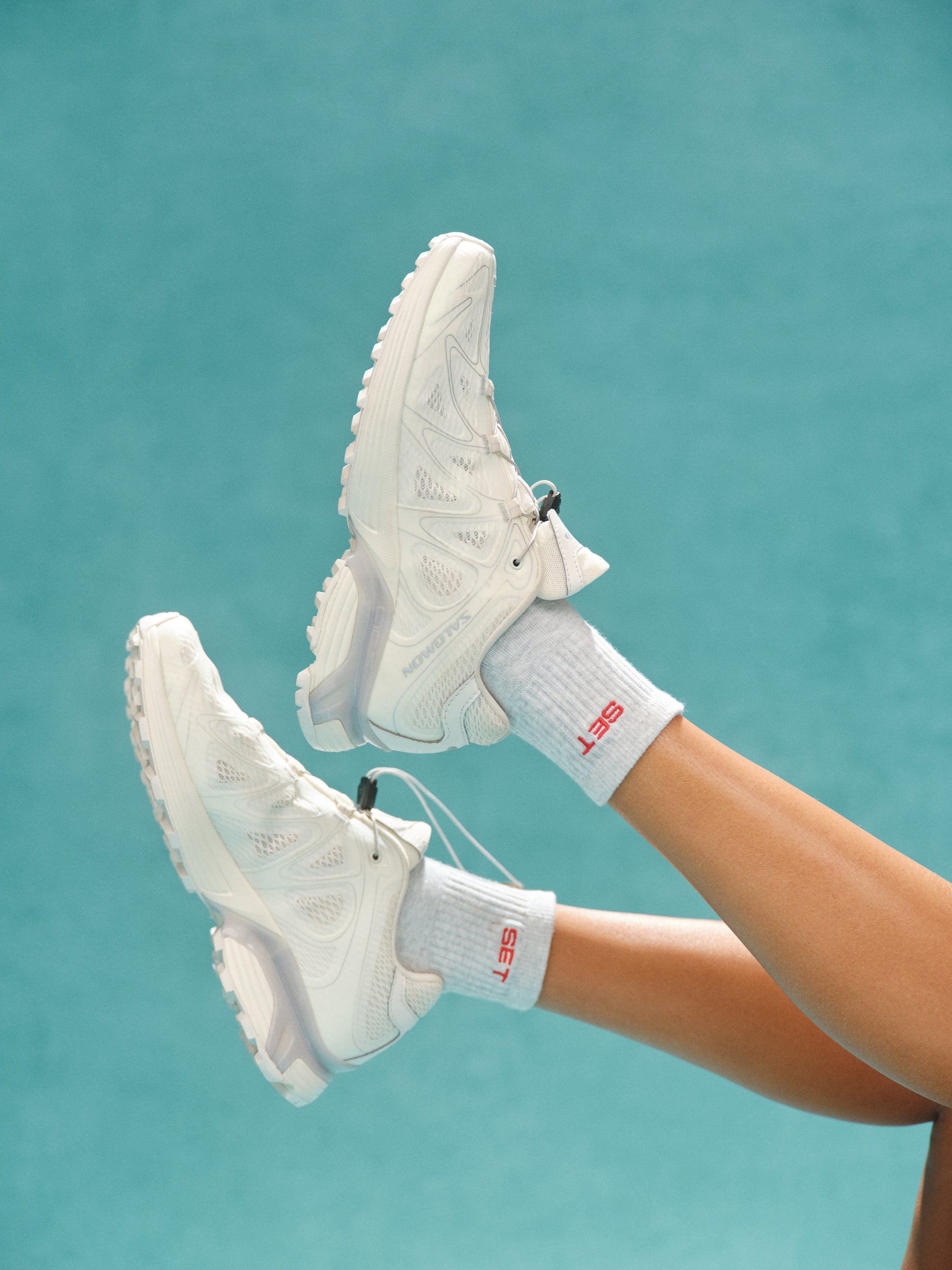 White sneakers and socks with red text on a teal background