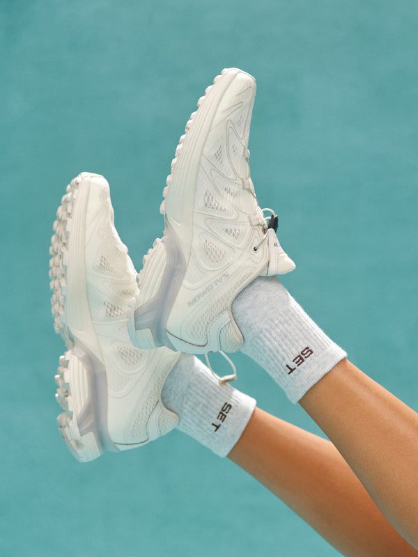 White sneakers and socks against a teal background