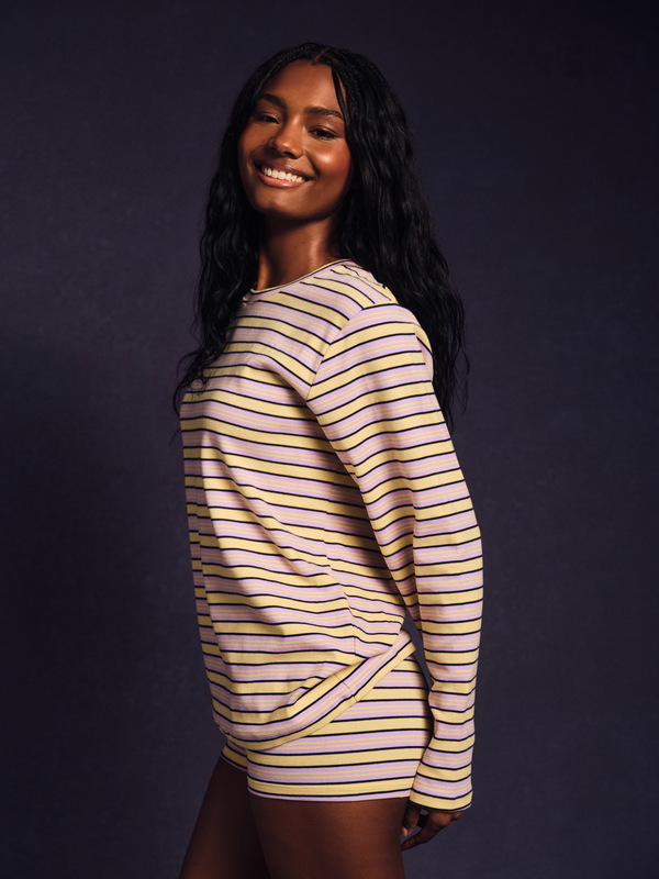 Woman wearing a striped long-sleeve shirt against a dark background 