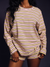 Person wearing a yellow and purple striped long-sleeve top and shorts on a dark background