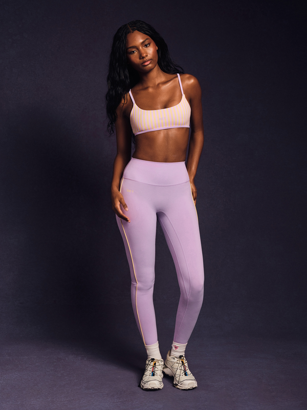 Woman wearing a sports bra and leggings on a dark background