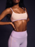 Person wearing a light purple sports bra and leggings with a dark background