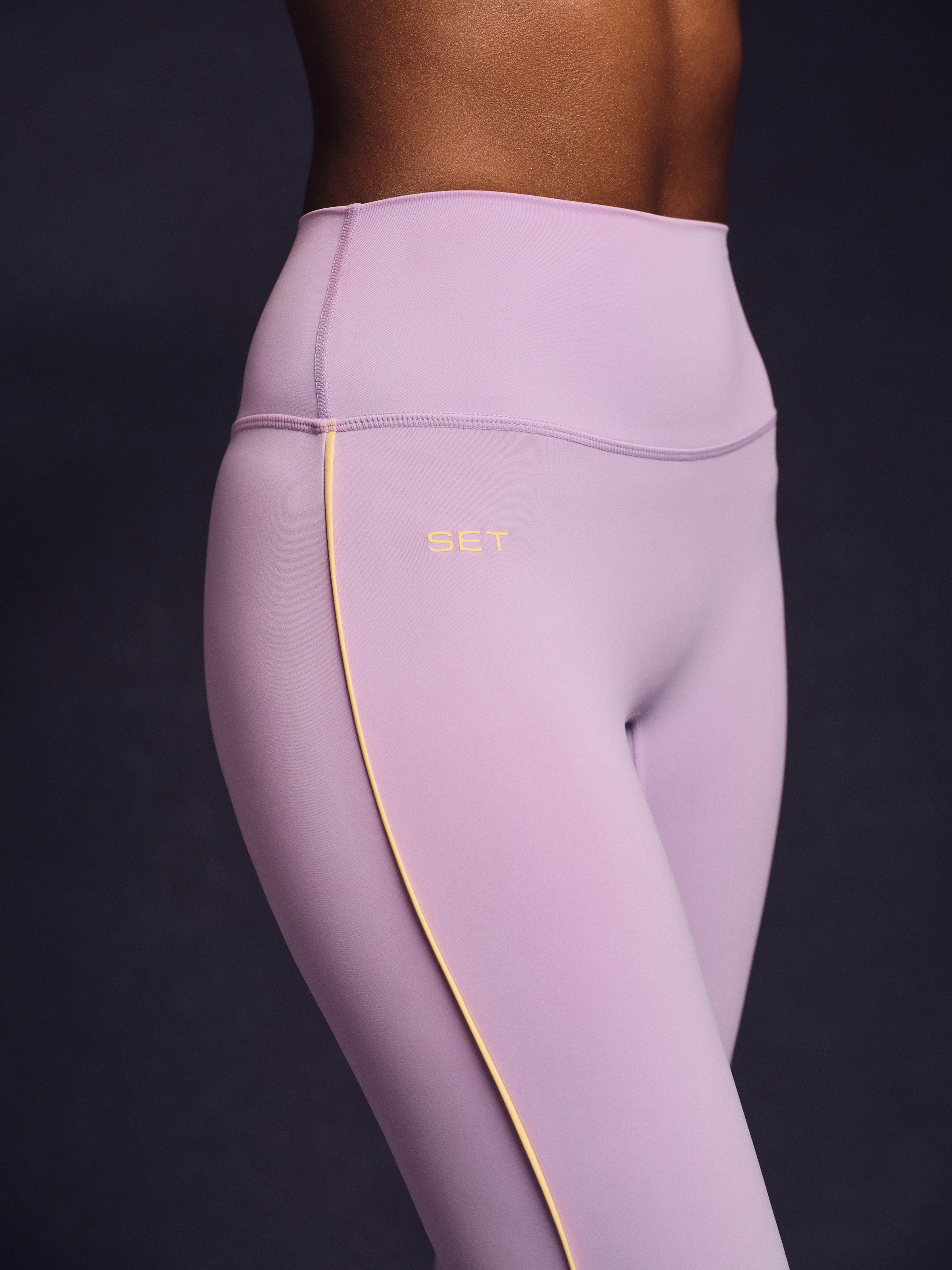 Light purple leggings with yellow piping on a dark background