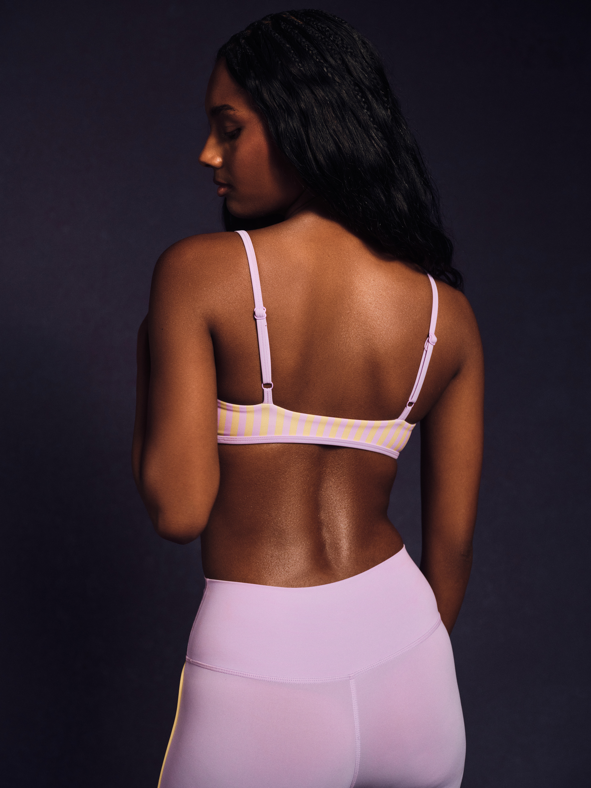 Woman wearing a light pink sports bra and leggings on a dark background