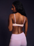 Woman wearing a light pink sports bra and leggings on a dark background