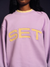 Person wearing a purple sweatshirt with 'SET' in yellow letters on a dark background