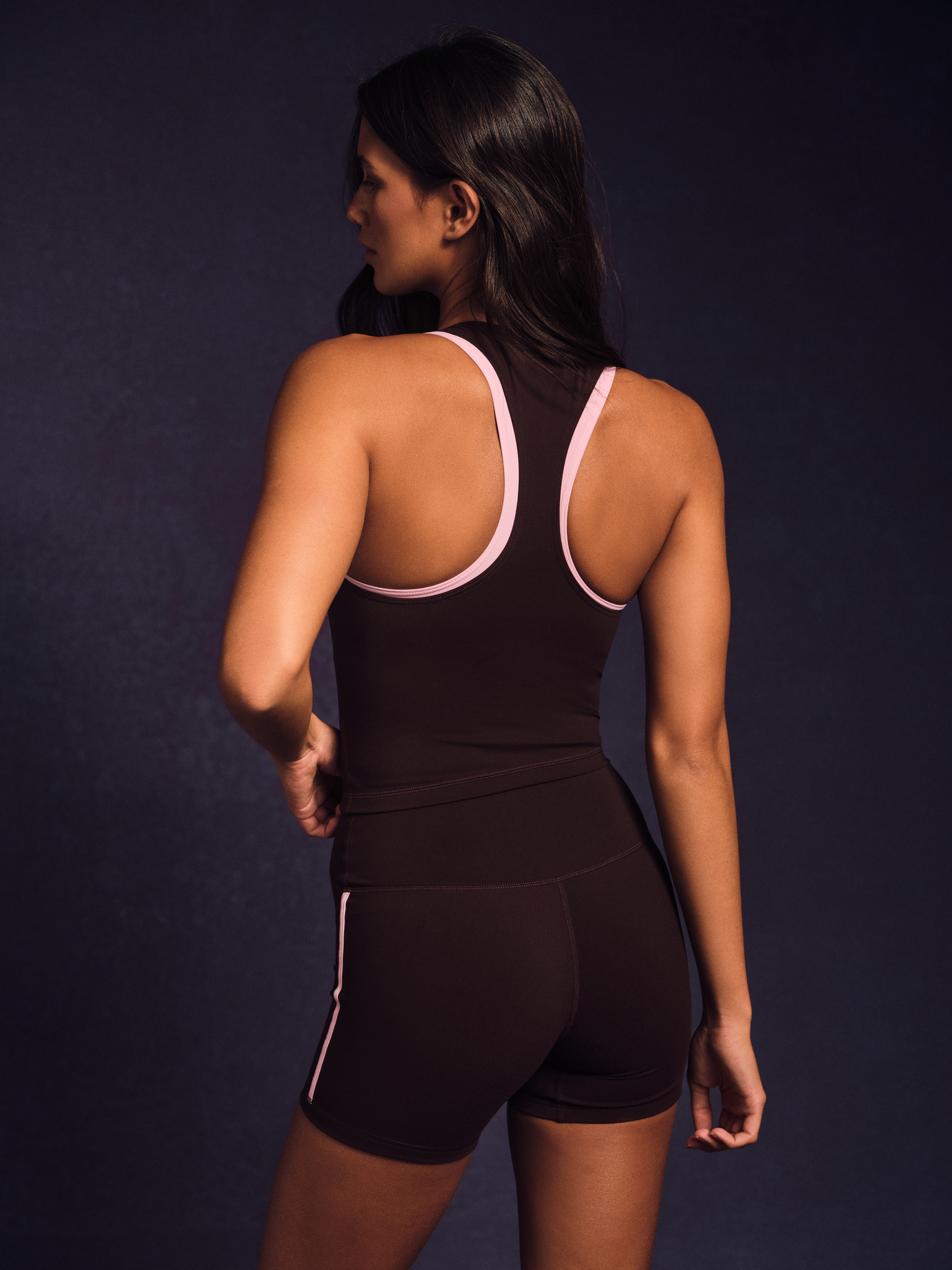 Woman wearing a black athletic outfit with pink accents on a dark background