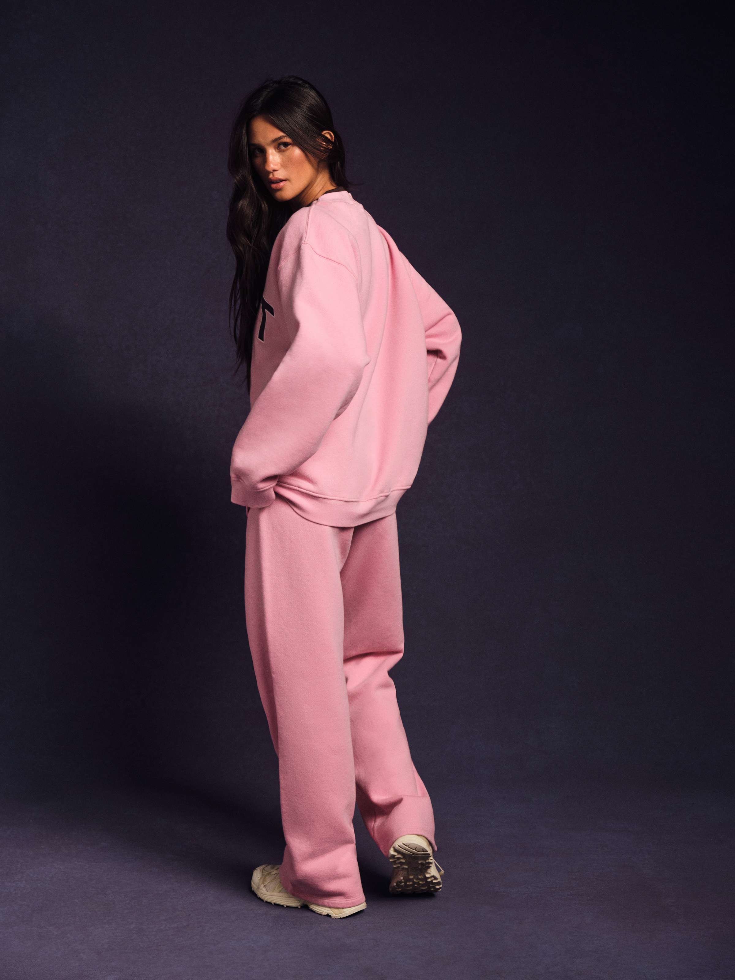 Person wearing a pink tracksuit against a dark background