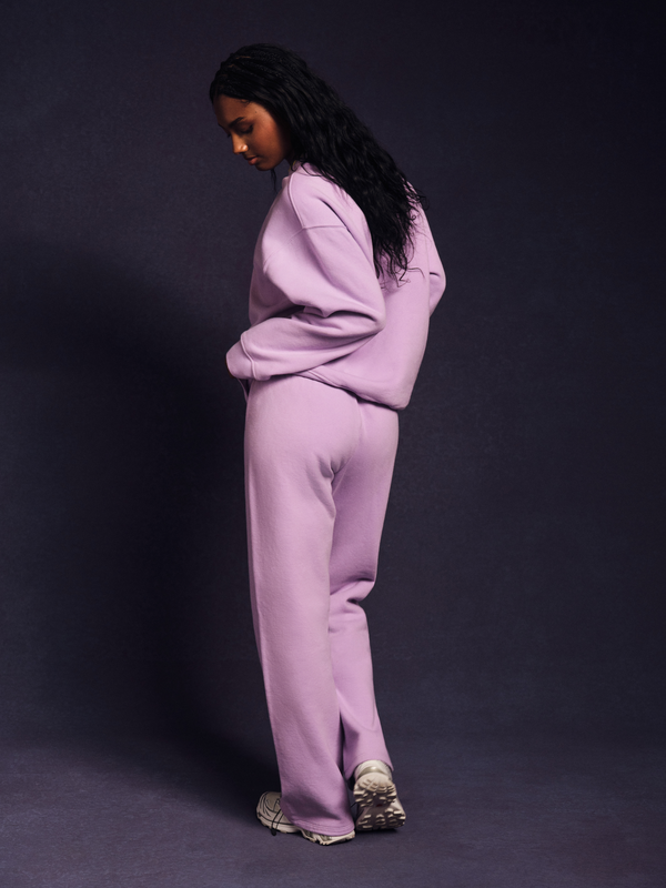 Person wearing a light purple tracksuit against a dark background