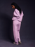 Side profile of a person wearing a light purple tracksuit against a dark background