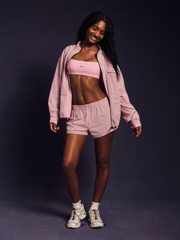 Woman wearing a pink athletic outfit on a dark background