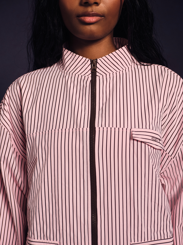 Person wearing a pink and white striped jacket with a dark background
