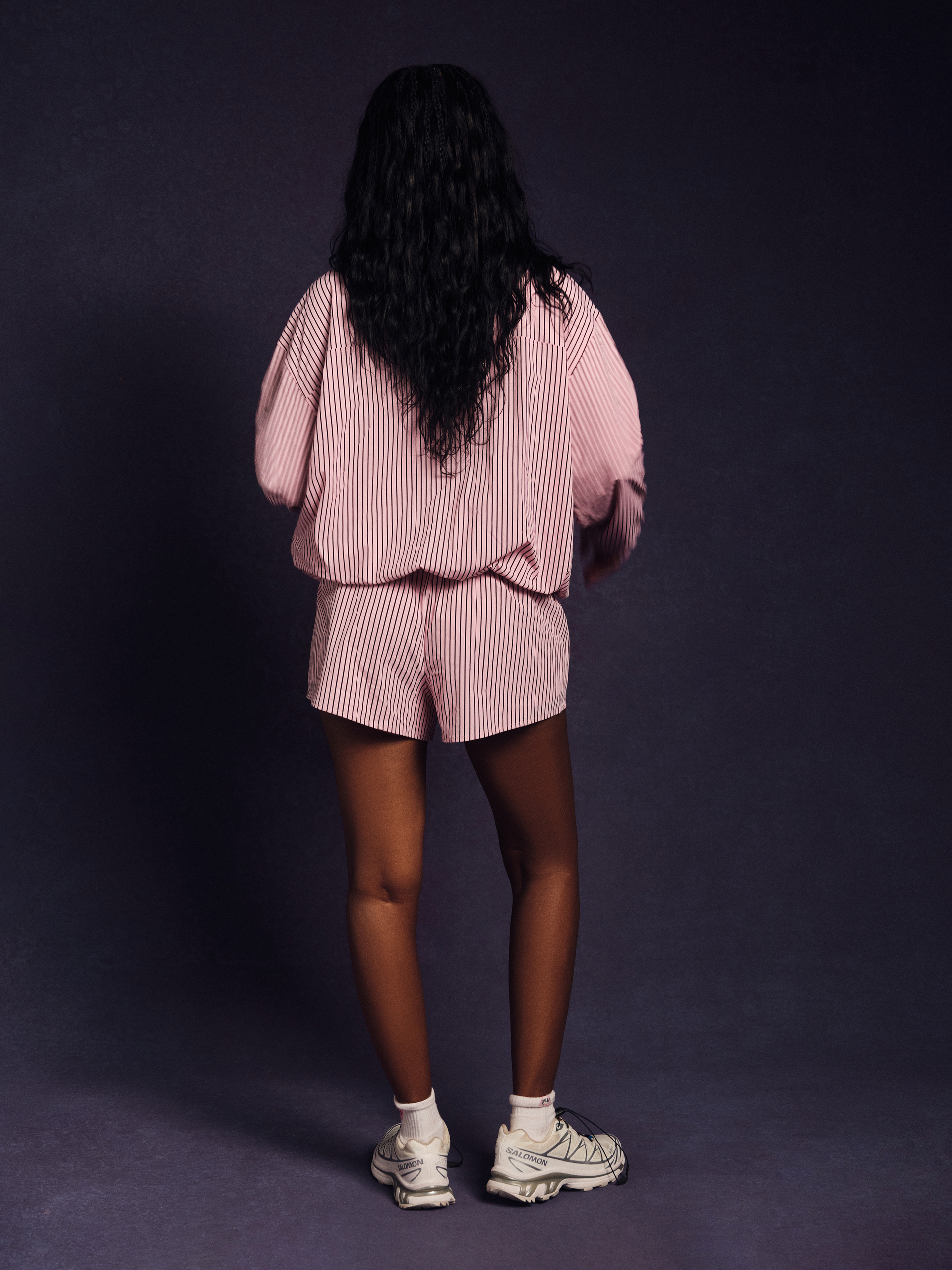 Person wearing a pink striped outfit on a dark background