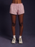 Person wearing pink striped shorts and white sneakers on a dark background