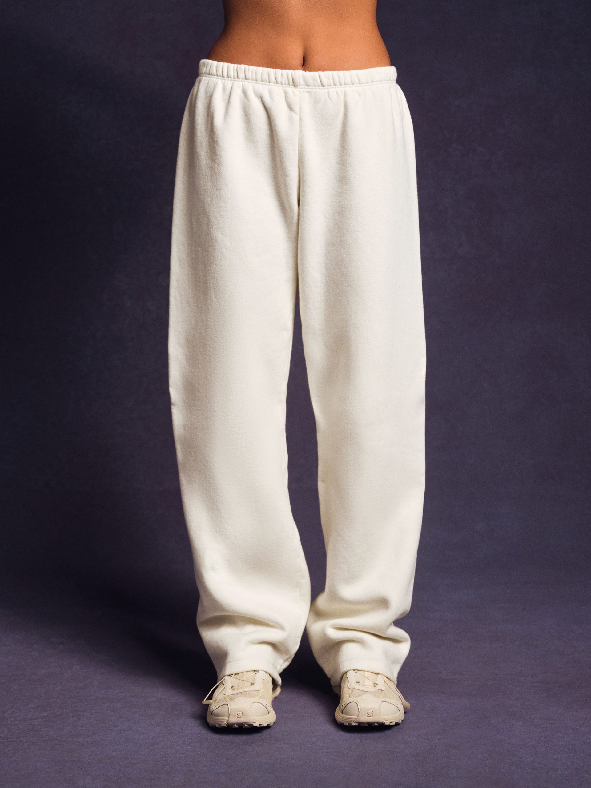 White sweatpants worn by a person on a dark background