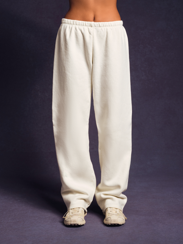 White sweatpants worn by a person on a dark background