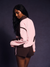 Woman wearing a pink and brown outfit against a dark background