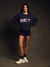 Person wearing a navy blue sweatshirt with 'SET' text on a dark background