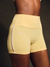 Beige athletic shorts with a brand logo on a dark background <model-info>Umi wears a size XS and is 5’8½”, 23½” waist, 32B bust.</model-info>
