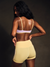 Woman wearing a yellow sports bra and shorts on a dark background