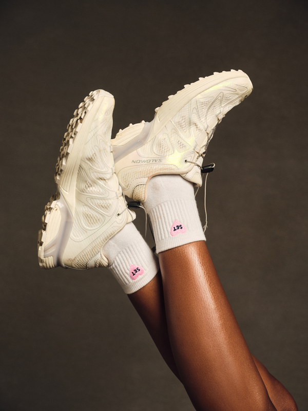 Person wearing white socks with hearts and white shoes.