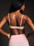 Woman wearing a pink sports bra and leggings against a dark background