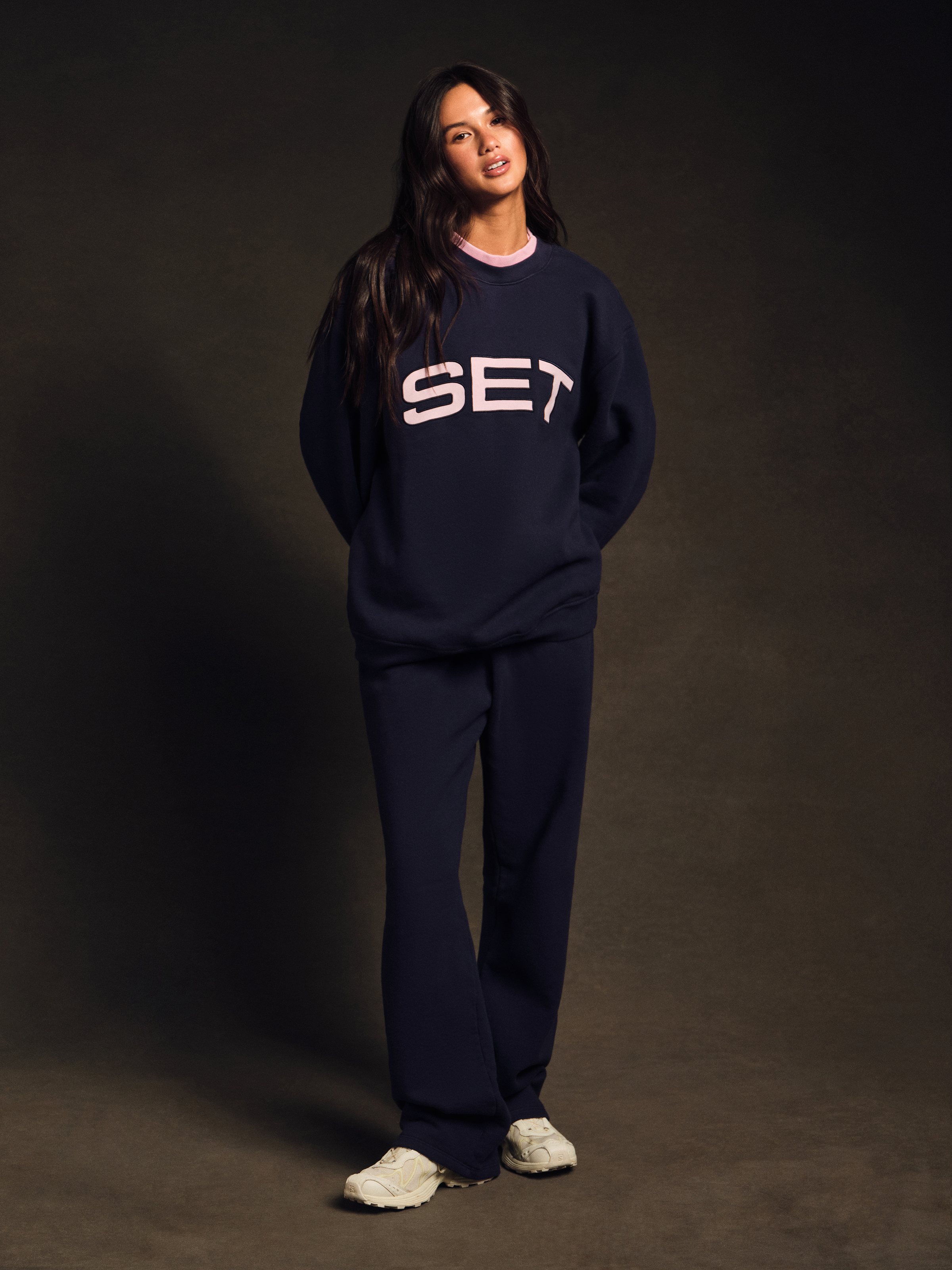 Person wearing a navy blue 'SET' sweatshirt and pants on a dark background 