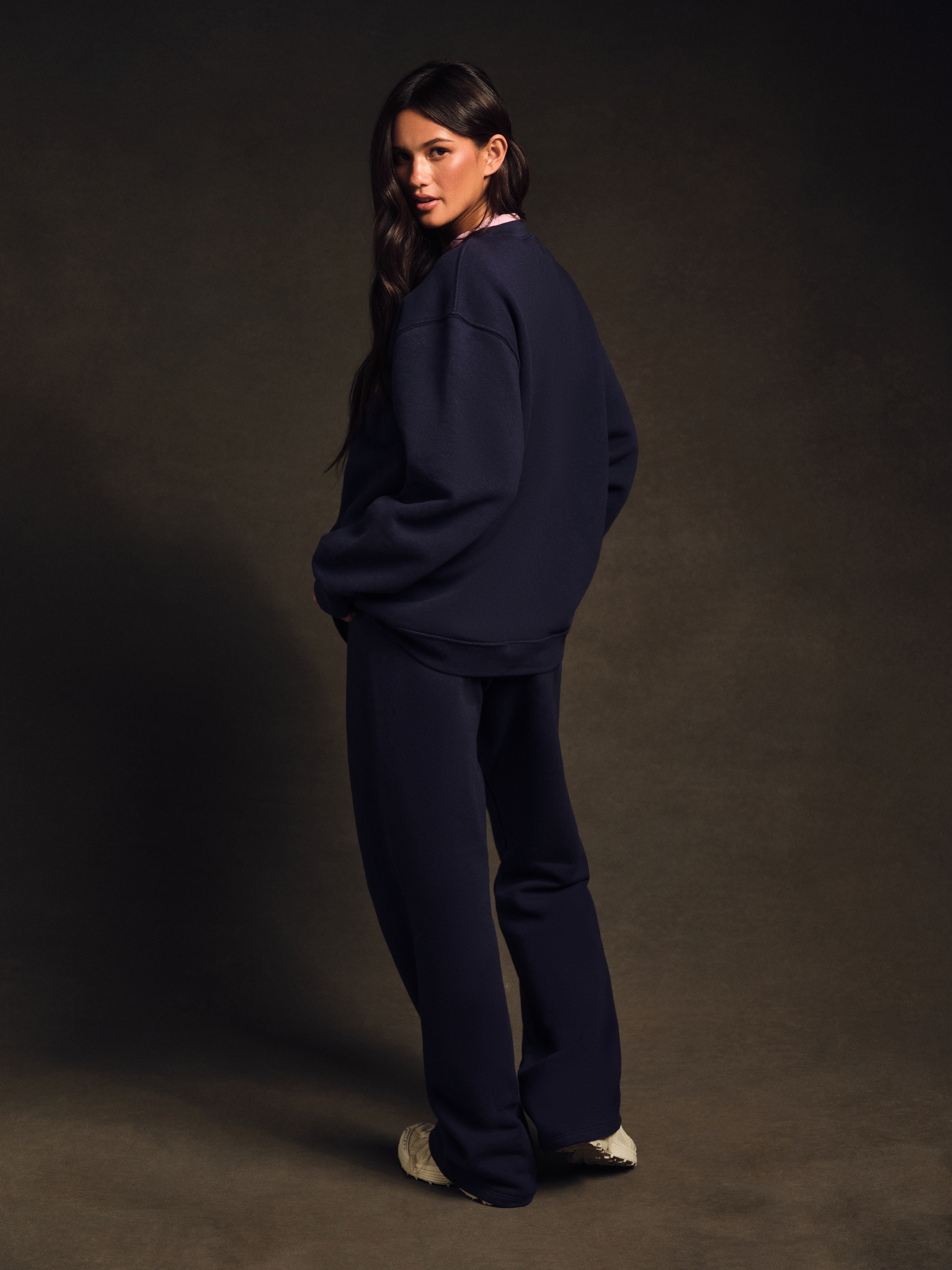 Woman wearing a navy blue outfit against a dark background
