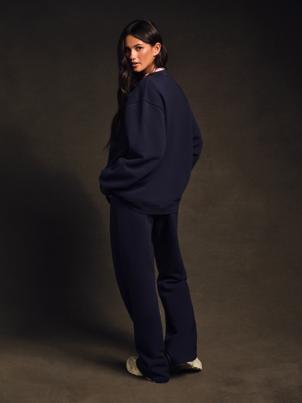 Woman wearing a navy blue outfit against a dark background