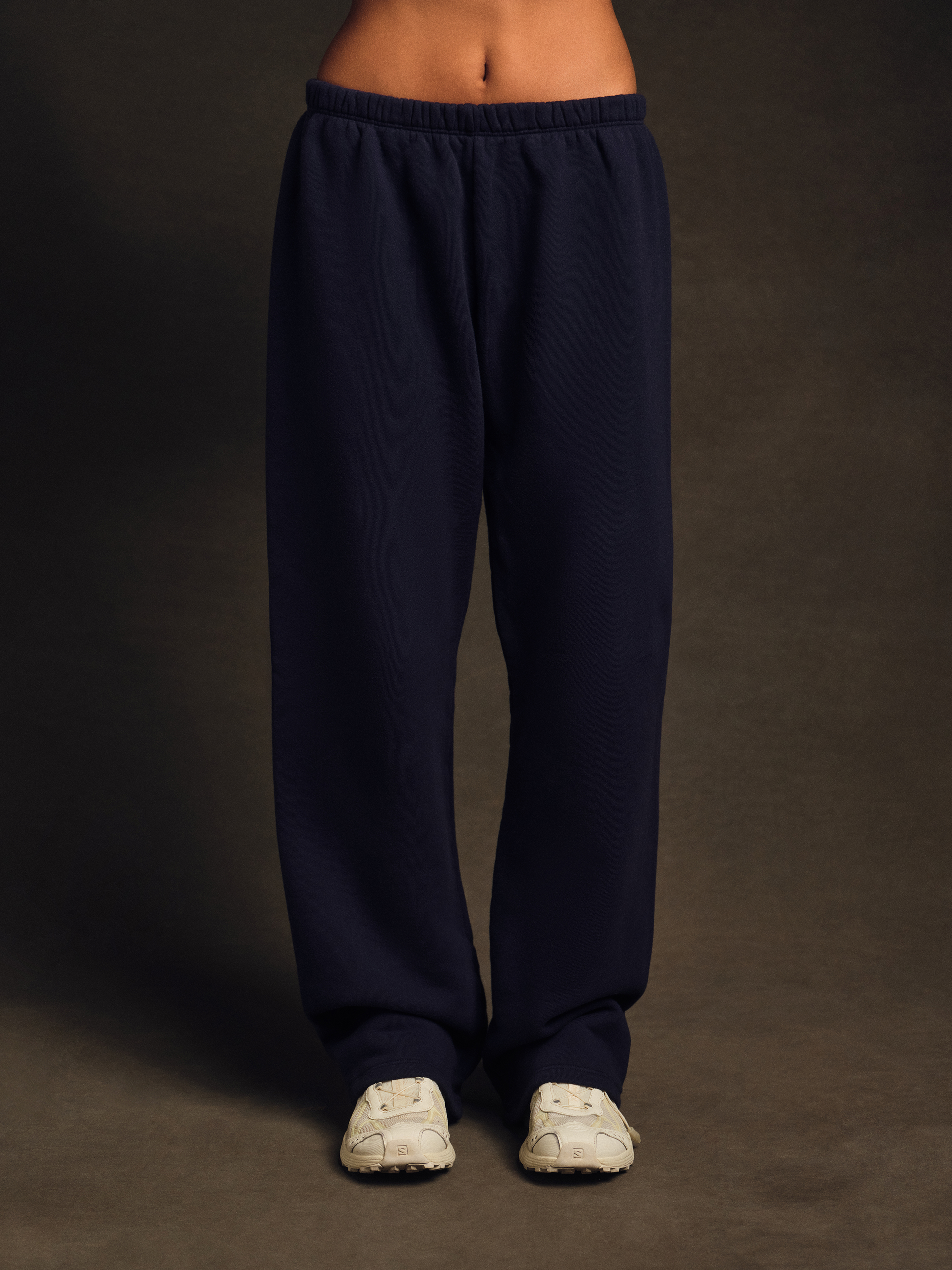 Navy blue sweatpants worn by a person on a dark background