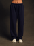 Navy blue sweatpants worn by a person on a dark background