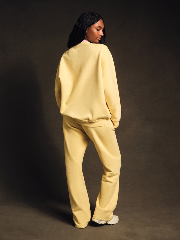 Person wearing a light yellow tracksuit against a dark background