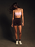 Person wearing a sports bra and shorts on a dark background