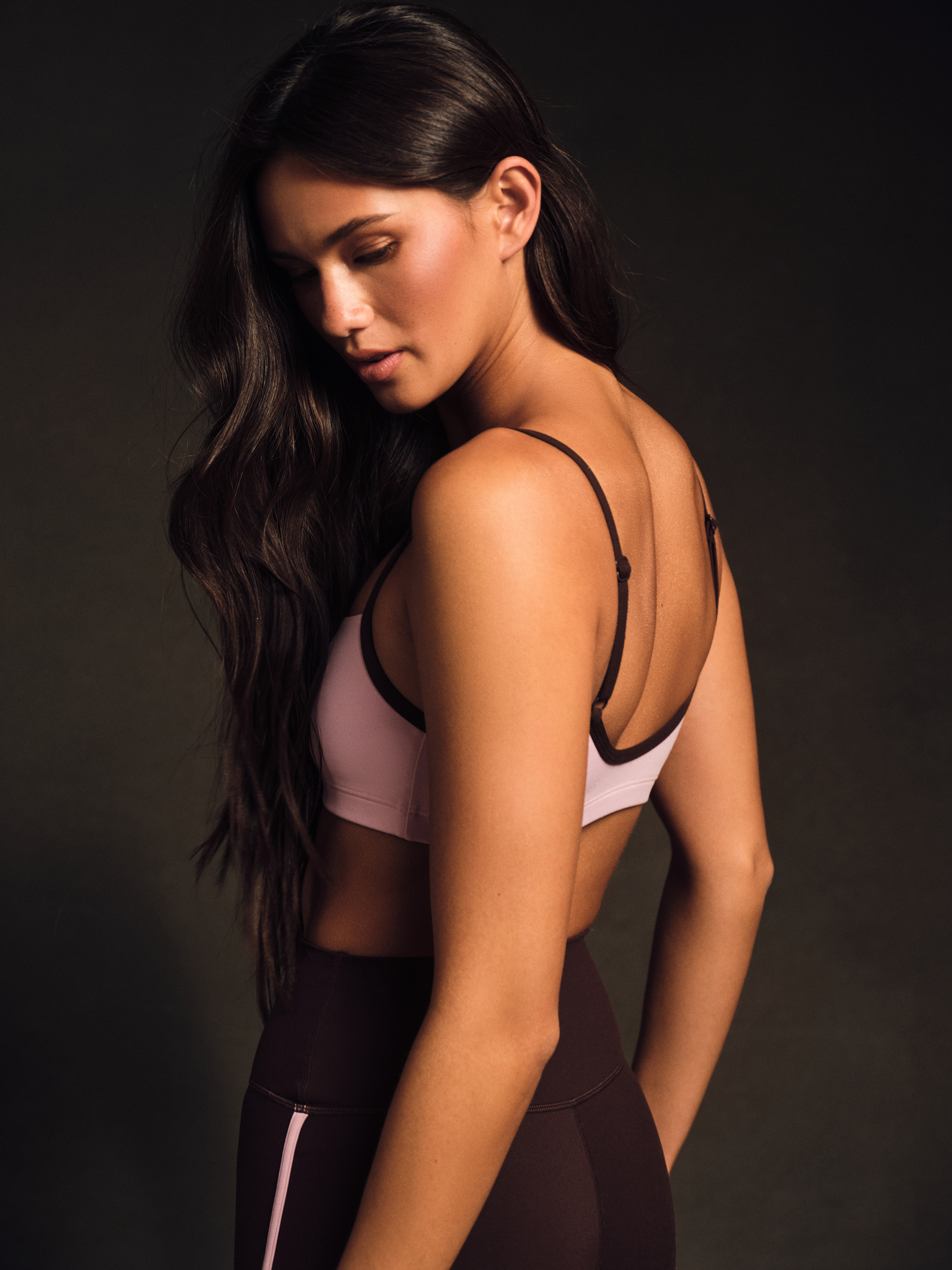 Woman wearing a sports bra and leggings against a dark background