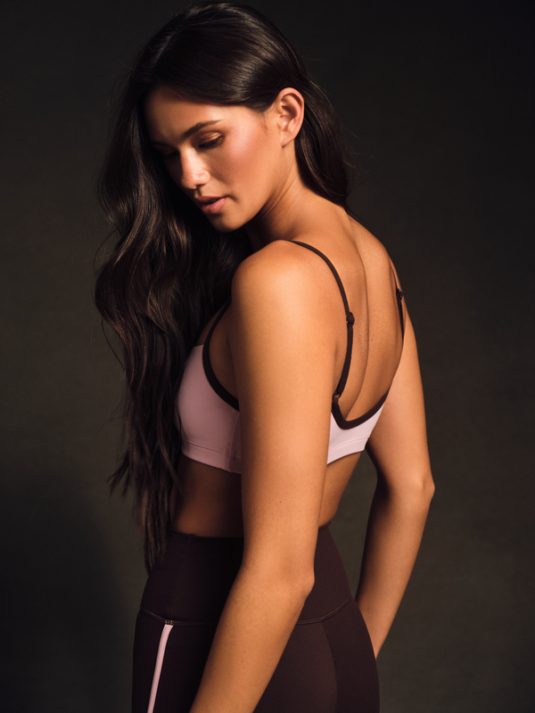 Woman wearing a sports bra and leggings against a dark background