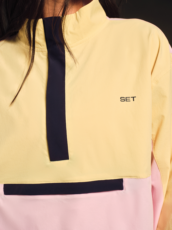 Close-up of a person wearing a yellow and pink jacket with a black stripe and 'SET' logo.
