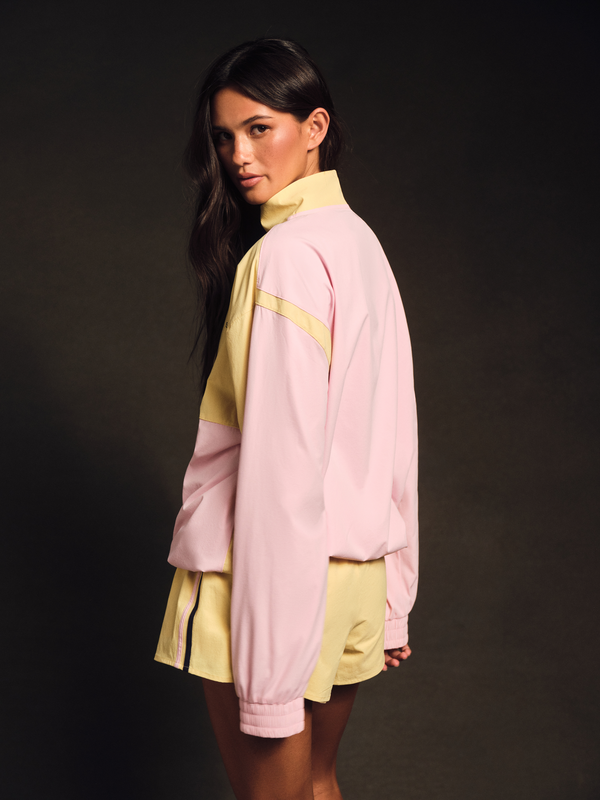 Woman wearing a pink and yellow jacket with a black background