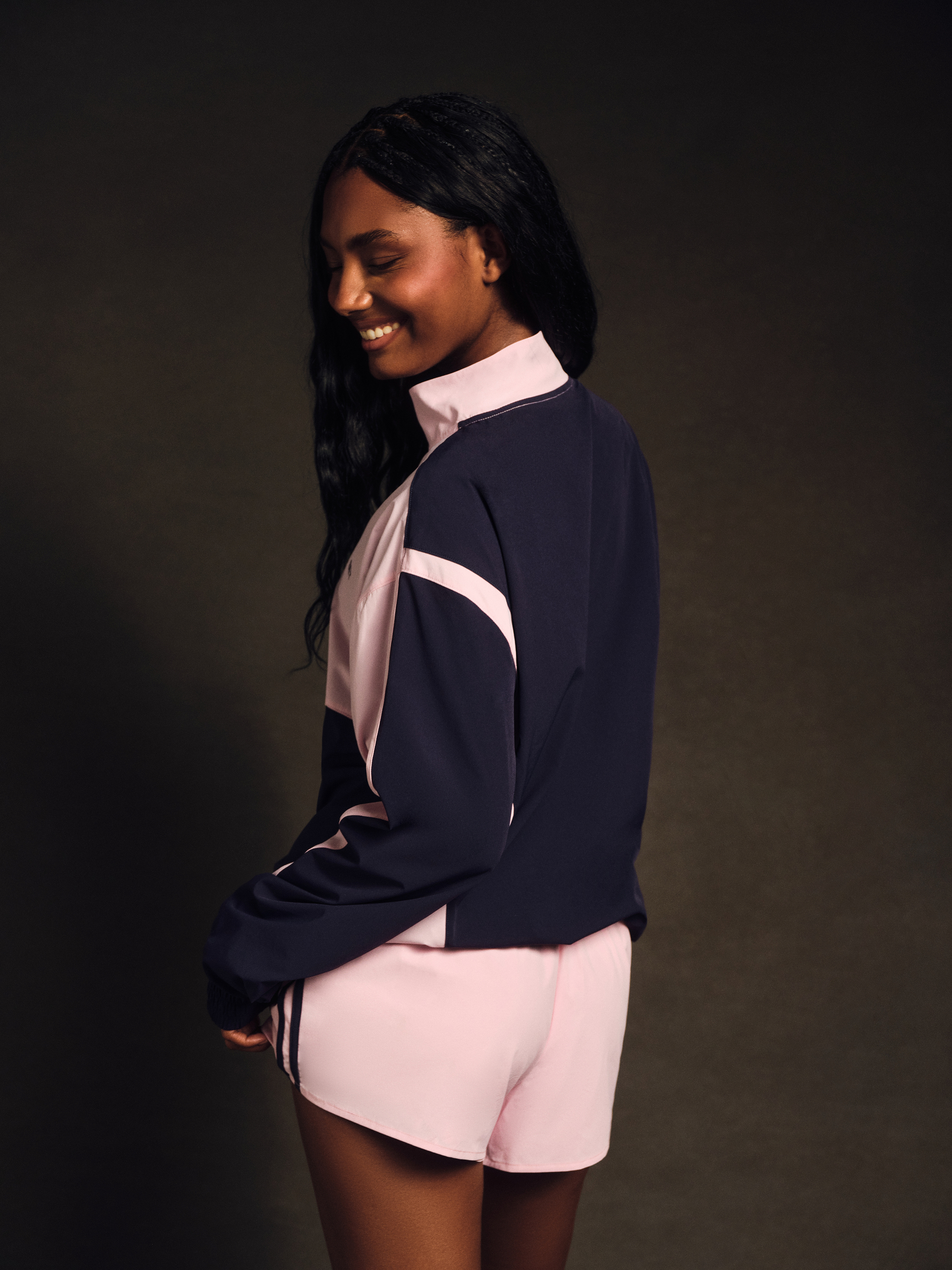 Woman wearing a navy and pink outfit against a dark background