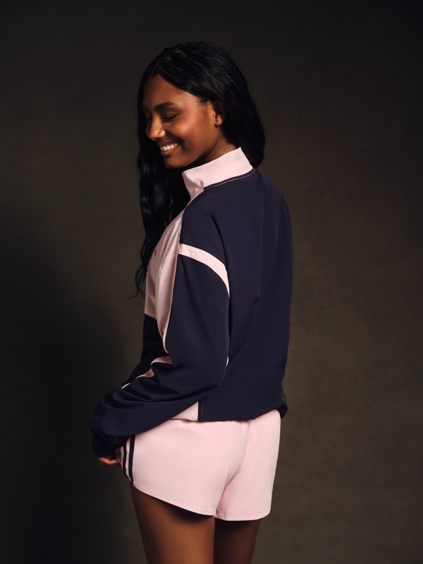 Woman wearing a navy and pink outfit against a dark background