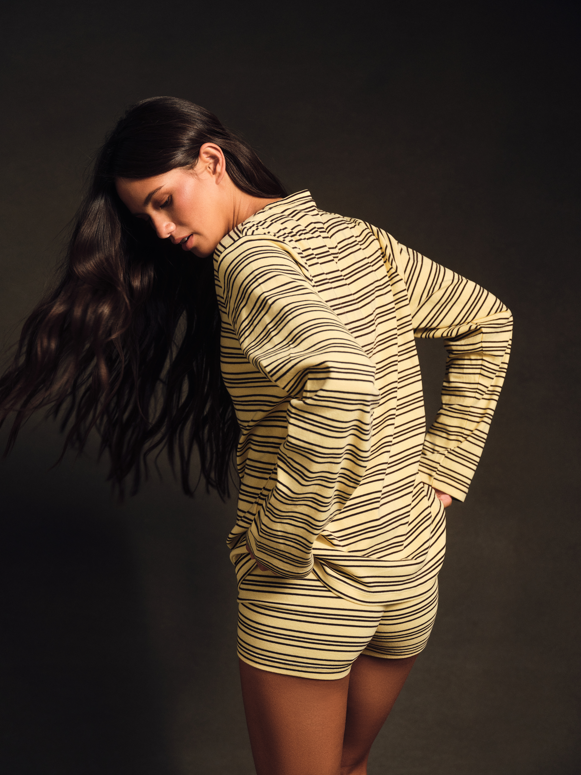 Woman wearing a striped outfit against a dark background