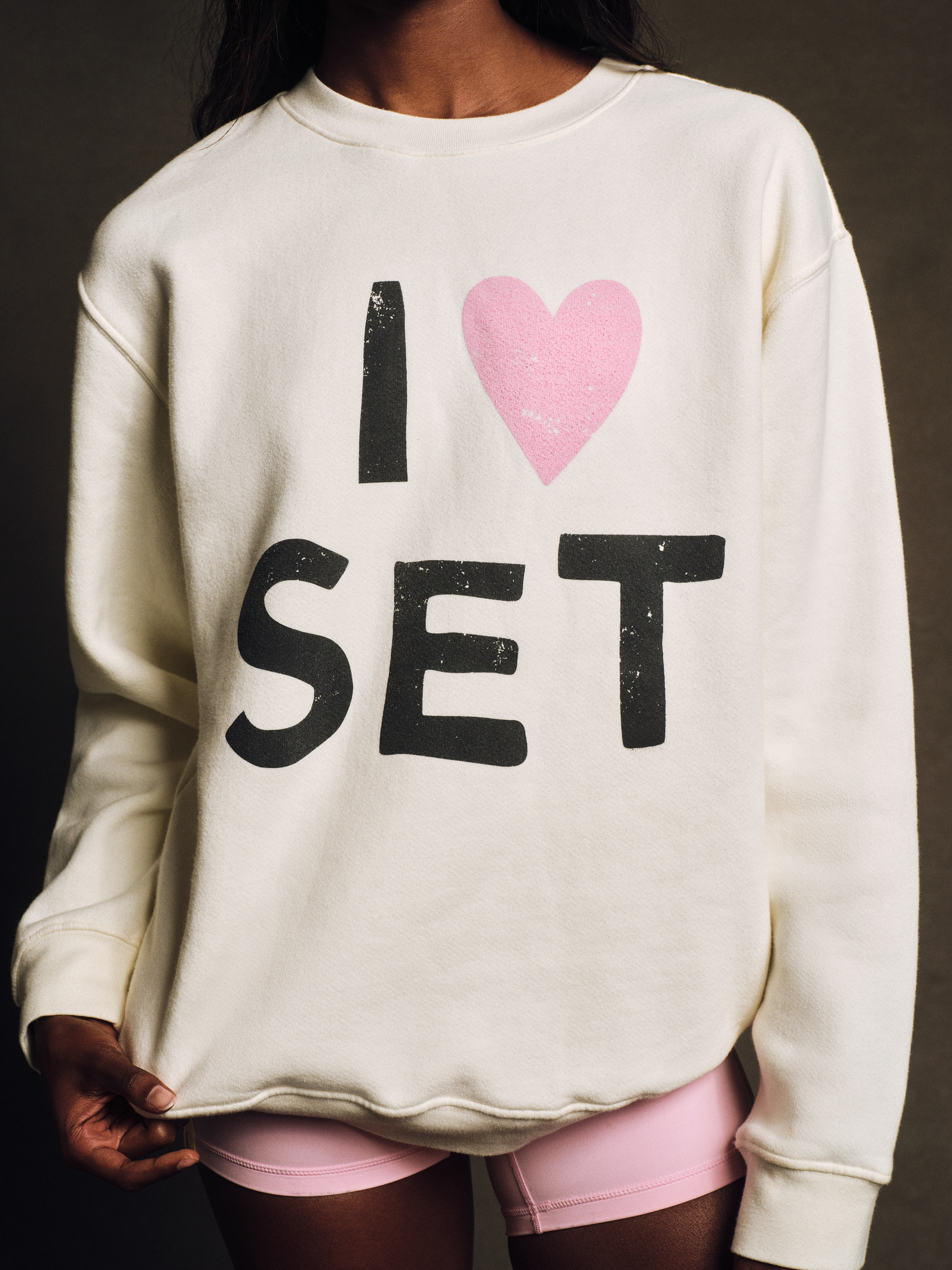 Person wearing a white sweatshirt with 'I ❤️ SET' text design.