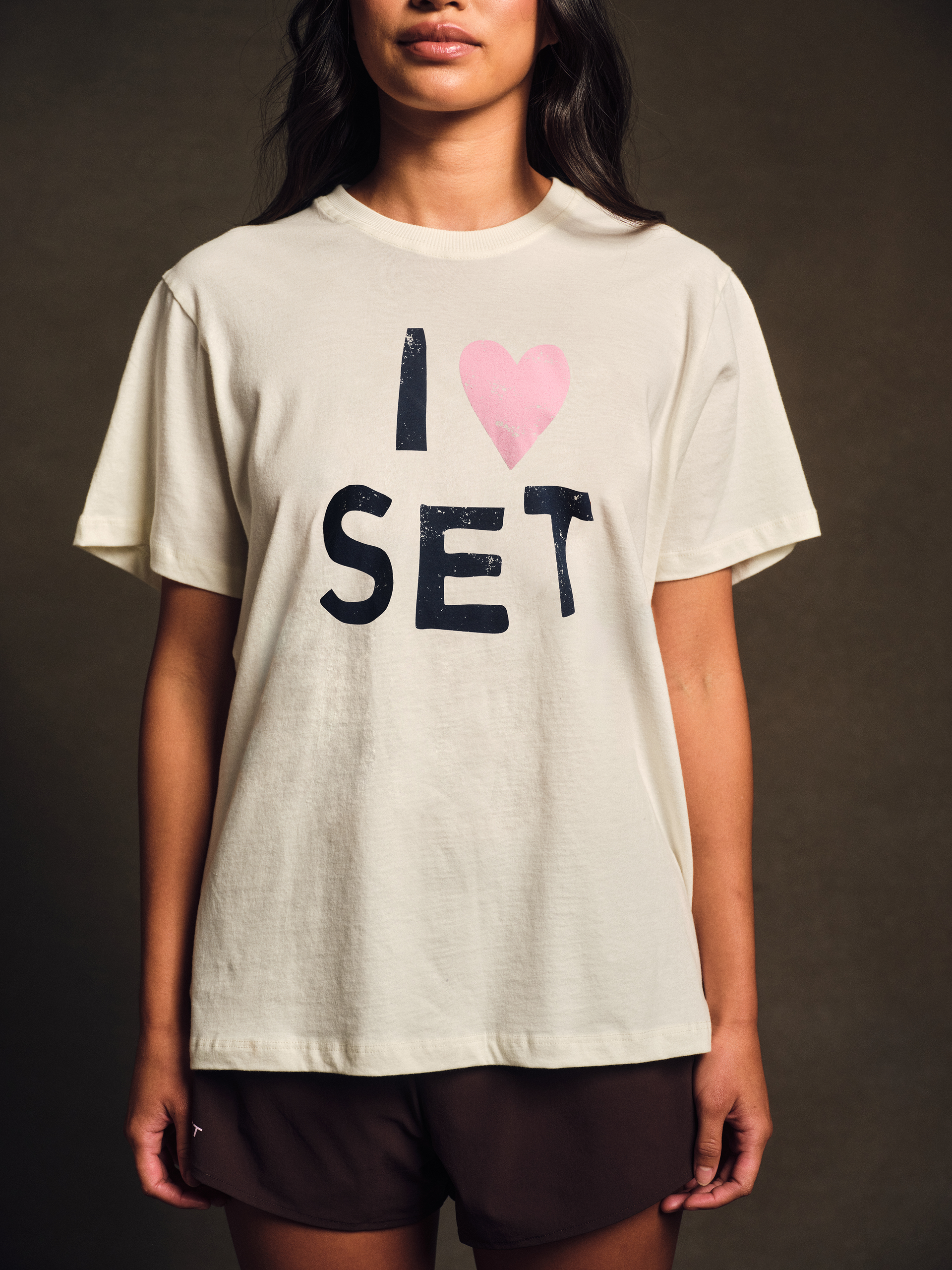 Person wearing a white t-shirt with 'I ❤️ SET' text on a dark background