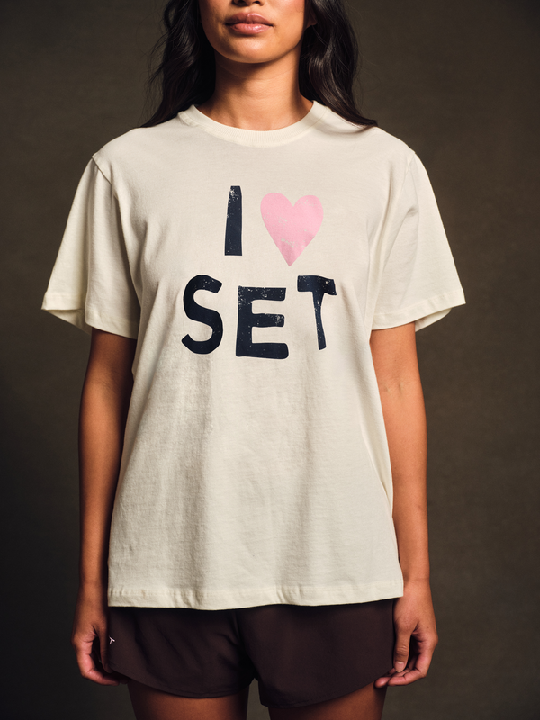 Person wearing a white t-shirt with 'I ❤️ SET' text on a dark background