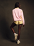 Person wearing a pink jacket and yellow shorts on a dark background