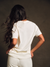 Person wearing a white t-shirt and pants against a dark background