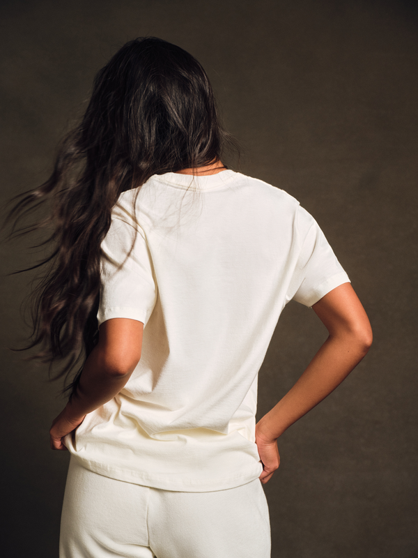 Person wearing a white t-shirt and pants against a dark background