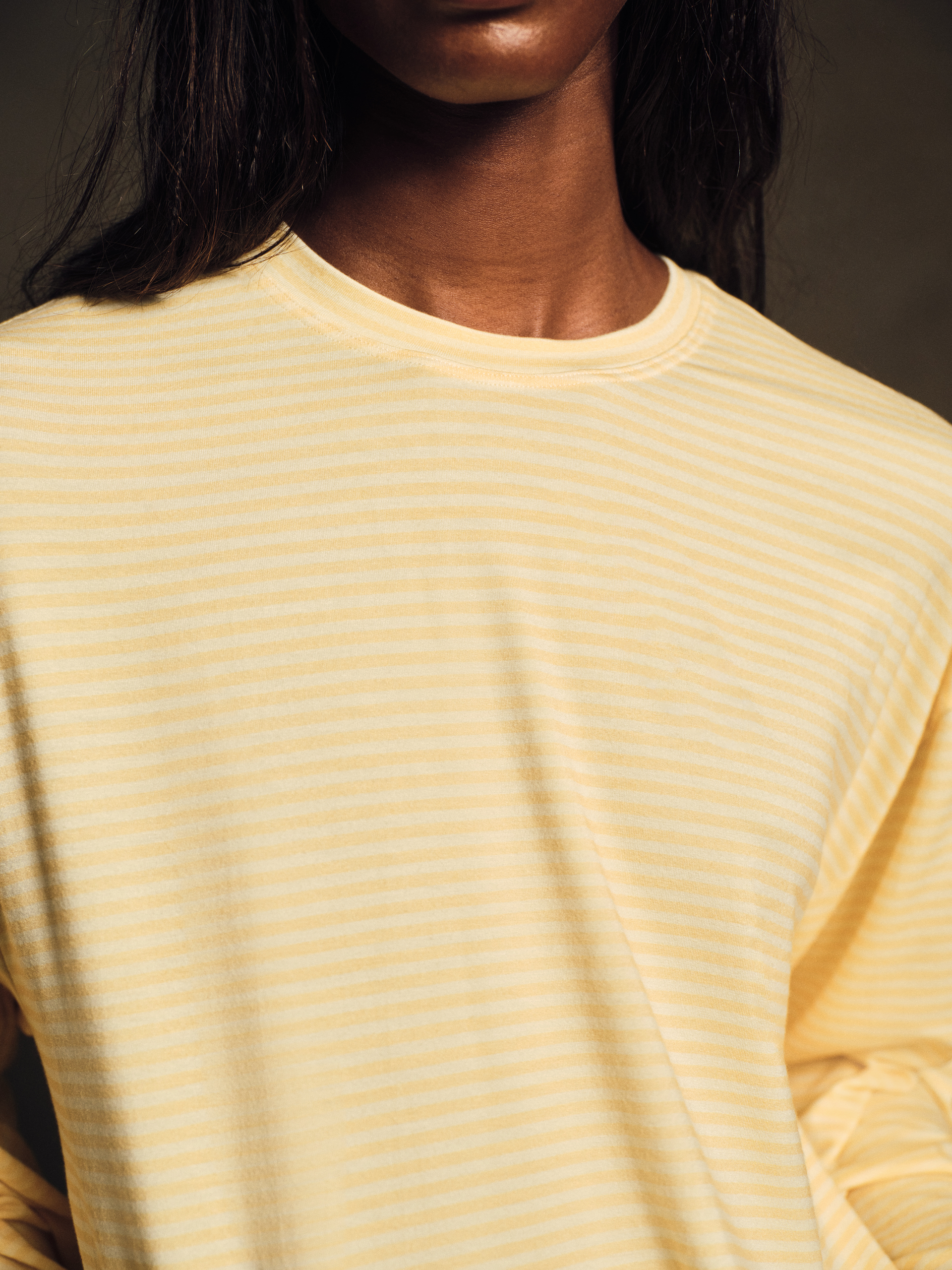 Close-up of a person wearing a yellow striped long sleeves against a dark background
