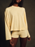 Woman wearing a yellow long-sleeve top and shorts against a dark background