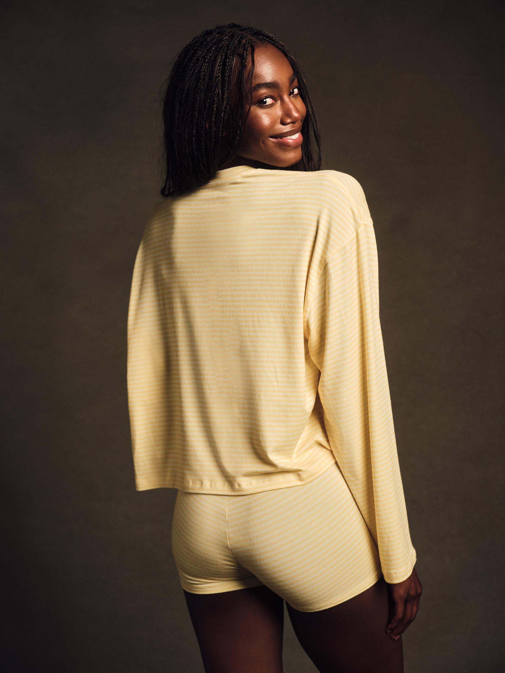 Woman wearing a beige long-sleeve top and shorts against a dark background <model-info>Nina D wears a size S and is 5’10”, 24” waist, 31½" bust.</model-info>
